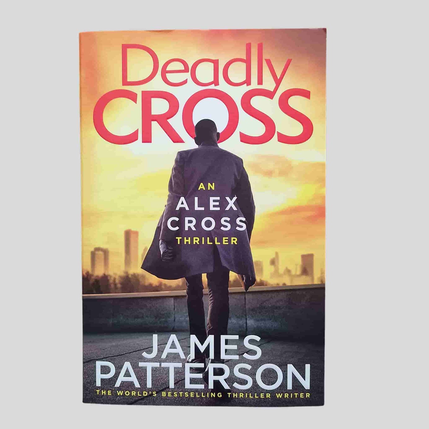 Deadly Cross by James Patterson – front cover of an Alex Cross thriller novel showing a silhouetted man against a city skyline at sunset