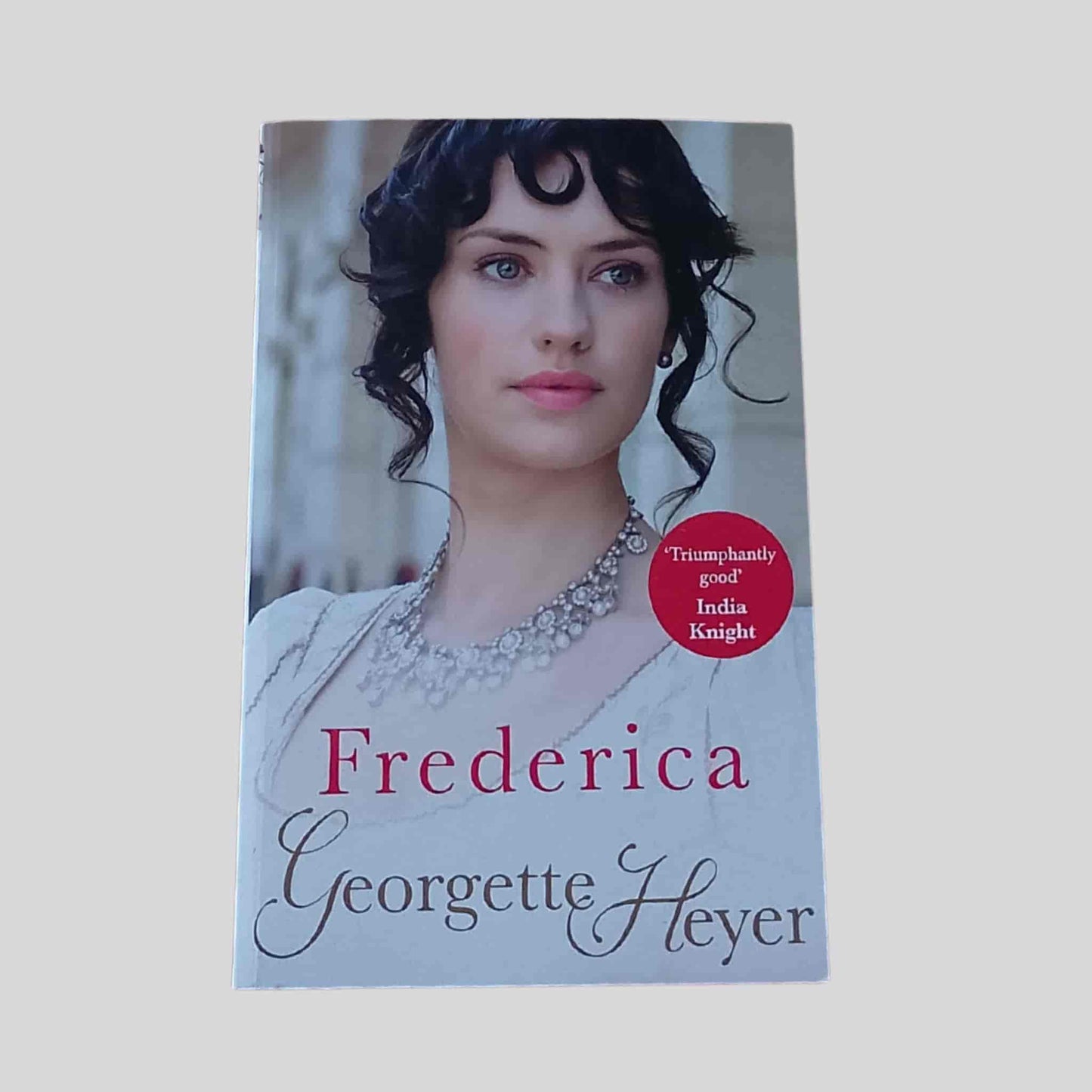 Paperback cover of Frederica by Georgette Heyer, featuring a Regency-era woman in an ivory gown and necklace, classic Regency romance novel