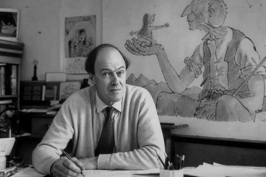 Roald Dahl sitting at his desk with illustrations of The BFG and Matilda behind him