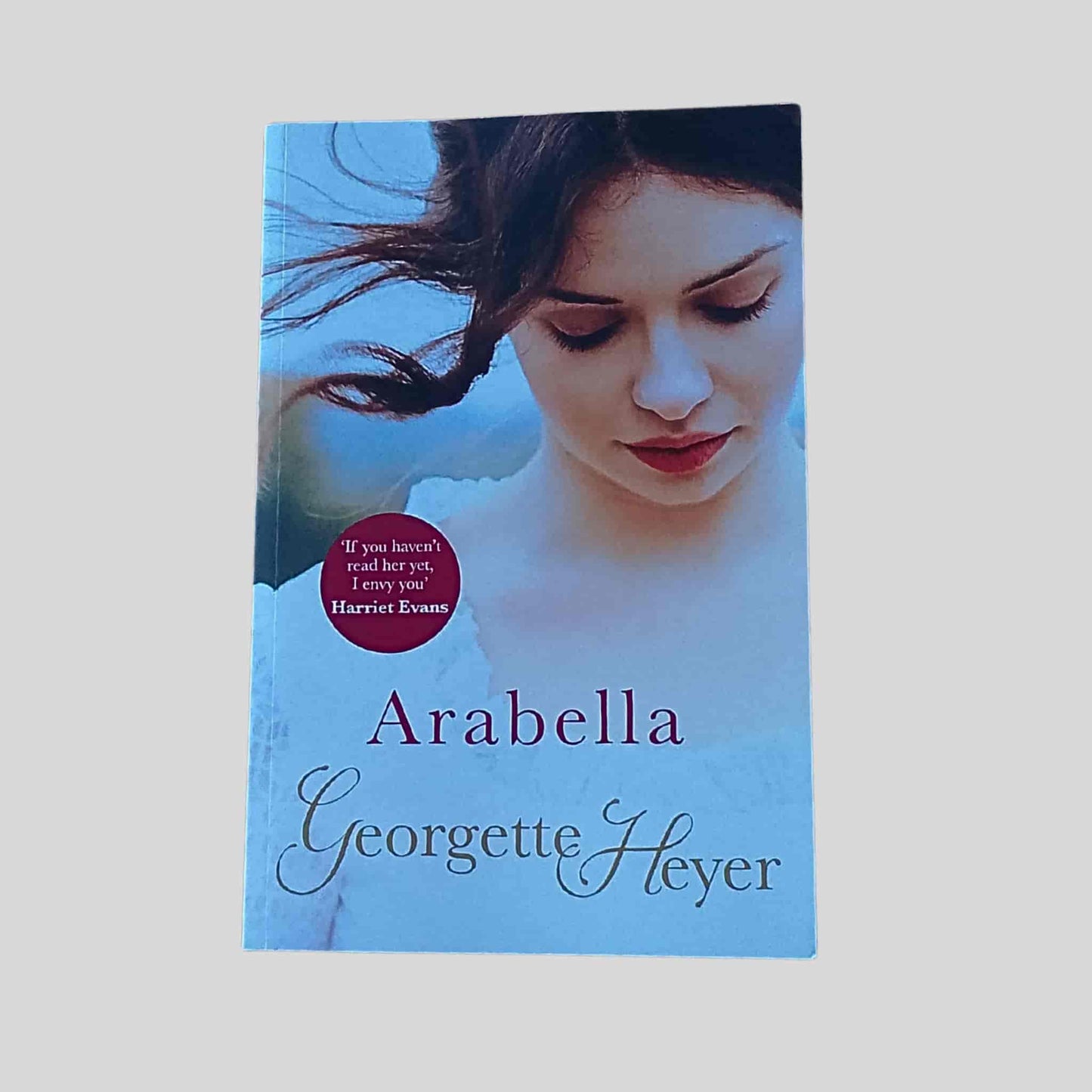 Book cover of 'Arabella' by Georgette Heyer showing the top half of a woman in a white Regency dress looking down