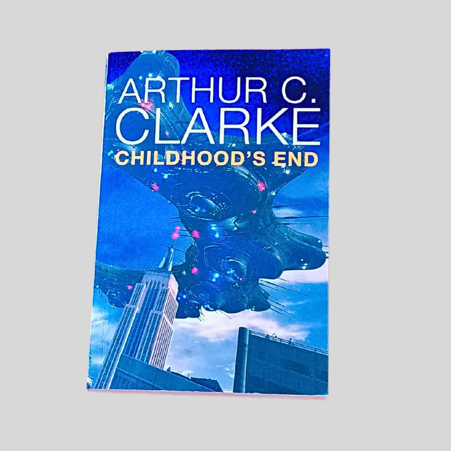 Book cover of 'Childhood's End' by Arthur C. Clarke with a futuristic cityscape and spaceship
