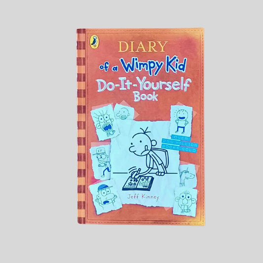 The front cover of the children's book called Diary of a Wimpy Kid Do It Yourself by Jeff Kinney showing Greg Heffley drawing at a desk