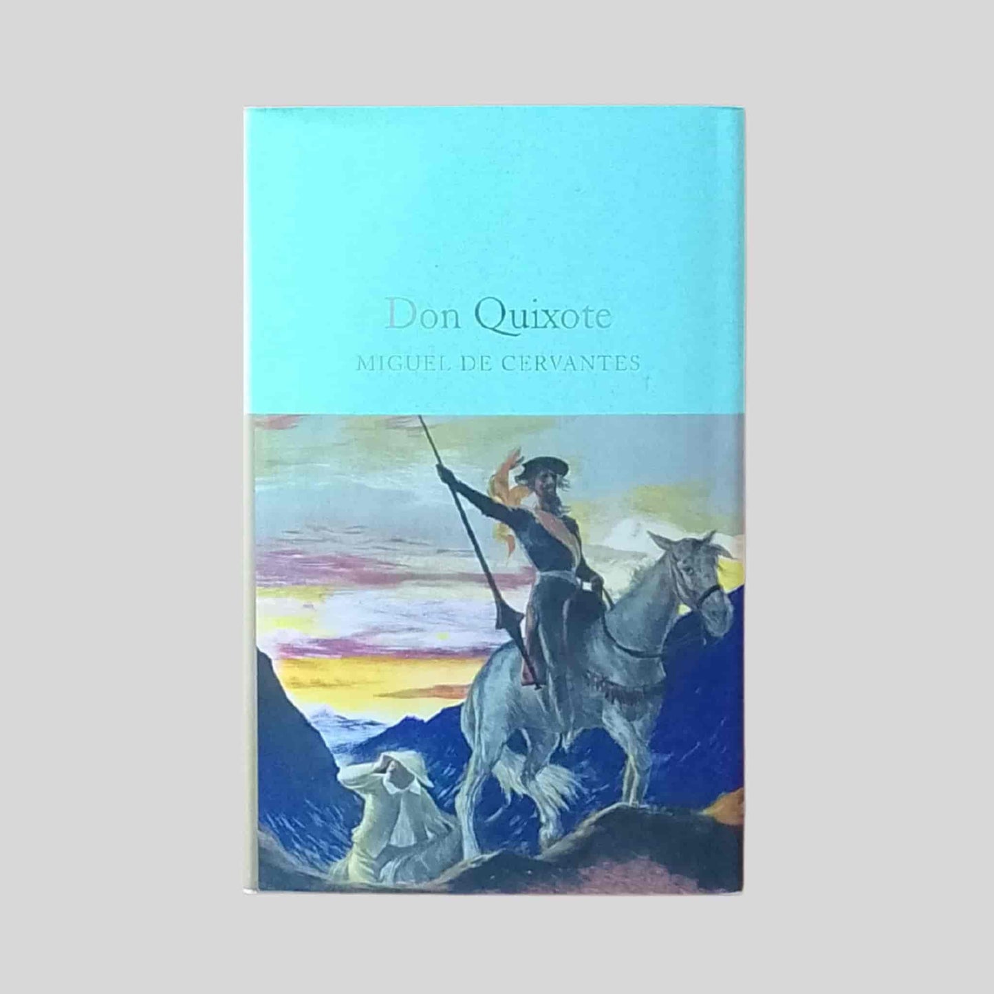 Paperback cover of Don Quixote by Miguel de Cervantes, depicting an illustrated scene of Don Quixote on horseback with a lance against a mountainous landscape