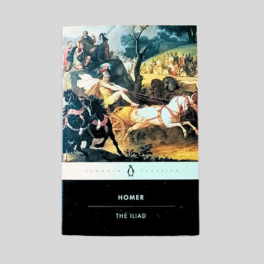 Paperback edition of The Iliad by Homer, featuring a classical painting of a chariot battle scene with horses and warriors