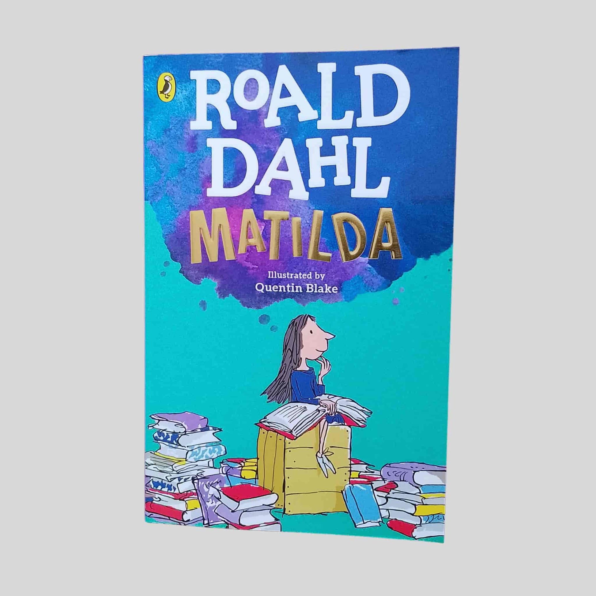 The cover of the kids book 'Matilda' by Roald Dahl with a colourful cartoon design of a girl with lots of books 