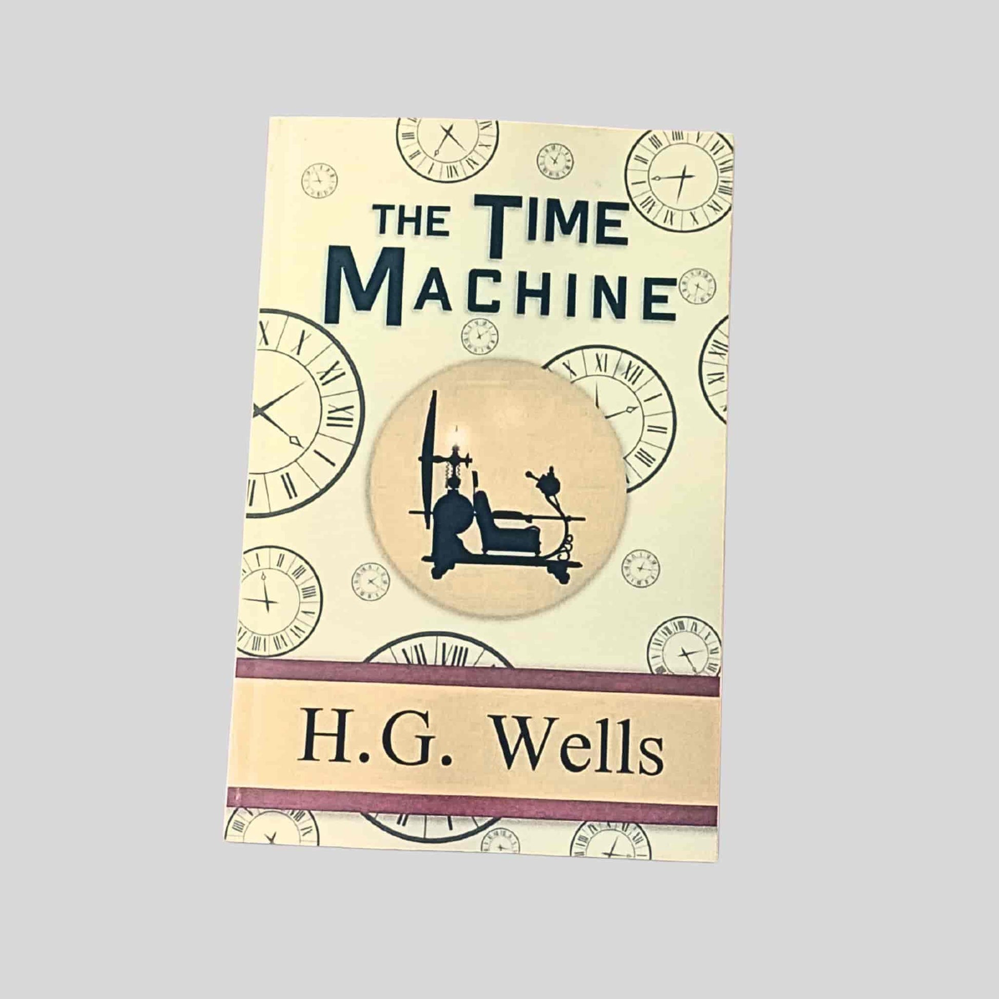 A cream paperback edition of The Time Machine by H. G. Wells, featuring a silhouette of a time traveller seated in a Victorian time machine, surrounded by clock illustrations
